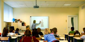 Teacher teaching class of students using interactive whiteboard